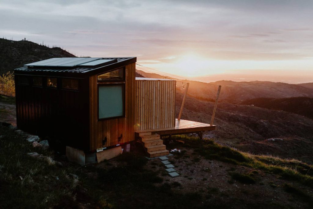 6 unique AirBNB homes in unique locations: a wooden home at the top of the hill at sunset