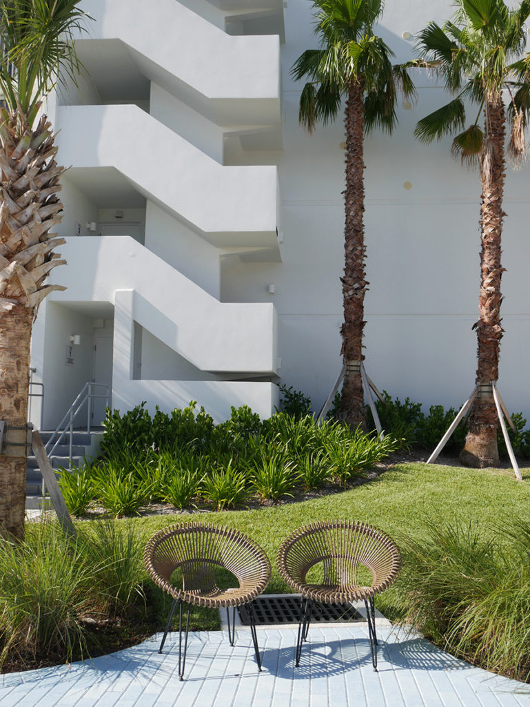 Staying at Plunge Hotel Lauderdale by the Sea - exterior view of the building with two round lounge chairs by the palm trees