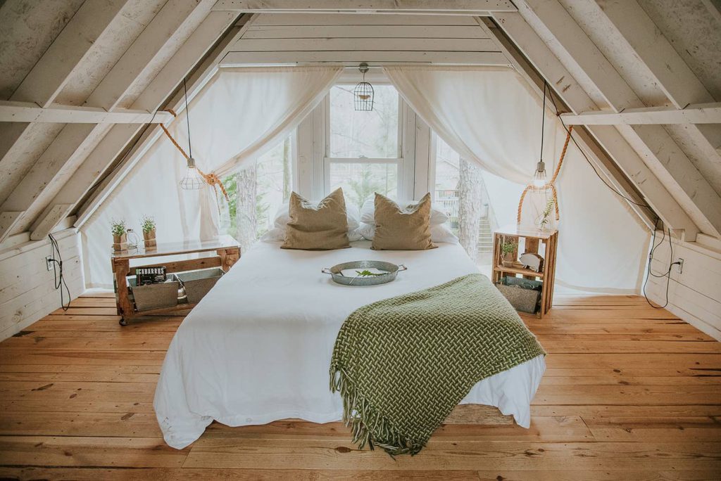 A-frame room with a large bed and clean white curtains 