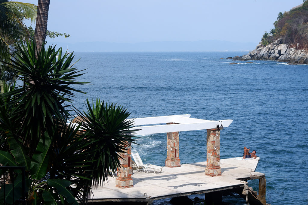 Hiking the Puerto Vallarta's Boca de Tomatlan trail: a man resting on a private white dock, blue ocean in the background