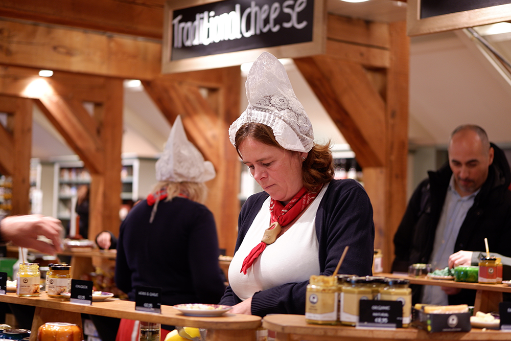 Amsterdam day trips: Zaanse Schans village in pictures: a traditionally dressed woman behind a cheese counter