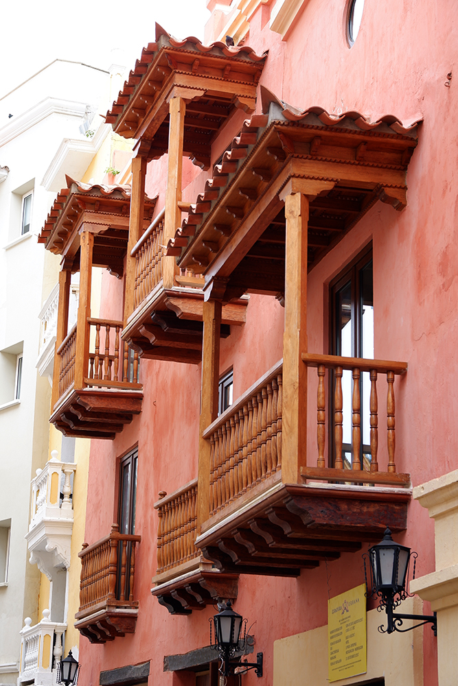 What to do and see Cartagena's Walled City and other Colombian basics: pink tinted building close up with decorative wooden balconies 