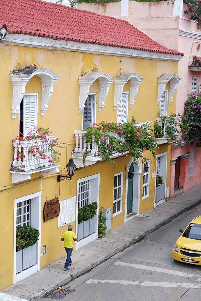 What to do and see Cartagena's Walled City and other Colombian basics high angle image of a sreet with a yellow building, a man in a yellow t-shirt walking along the road