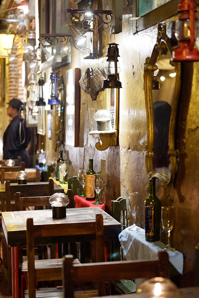 What to do and see Cartagena's Walled City and other Colombian basics - the city at night, restaurant tables lined up agains the wall with mirror and lights 