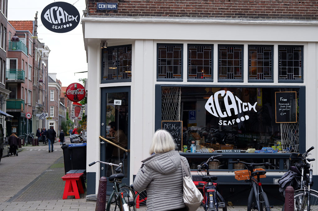 Exploring Jordaan, the historic neighbourhood in Amsterdam: a woman walking towards a seafood shop on the corner