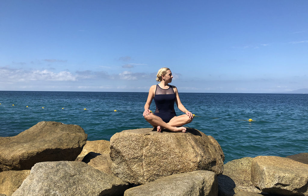 Review of Grand Fiesta Americana Puerto Vallarta: a blonde woman sitting cross-legged on a rock with the ocean in the background 