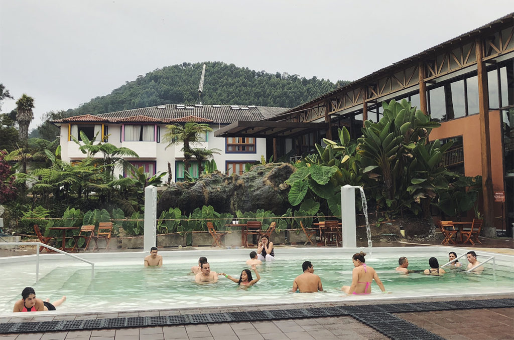 Termales El Otoño pool with people in it, you can see the mountain in the back of the building