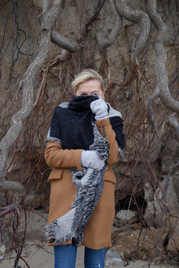 A women standing in front of a tree, covering her face with a scarf 