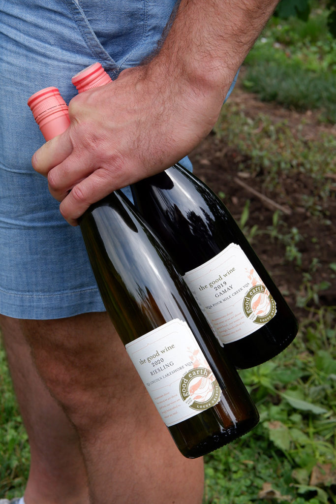 A guide to the Twenty Valley wine region: wine flight at The Good Earth Food and Wine Co. close up on two wine bottles in a men's hand