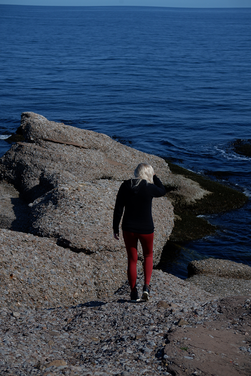 woman walking along a rocky path to the ocean Quebec Maritimes