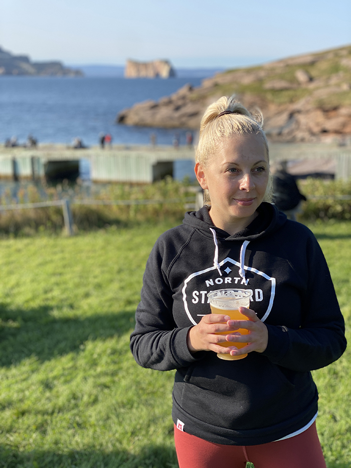 Destination guide: The great adventure through Quebec Maritimes - woman in the field holding a glass of beer 