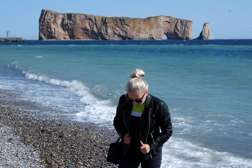 Perce rock and beach, a blonde woman standing in front of it