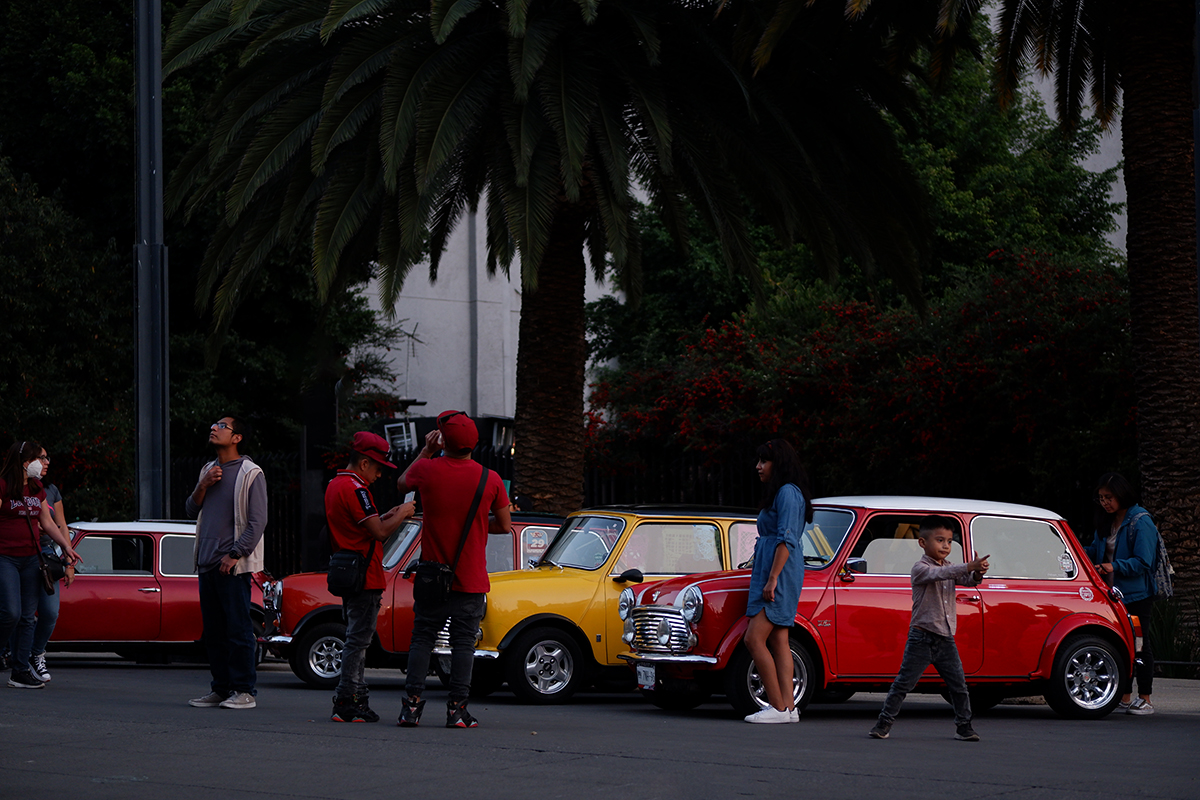 A group of people looking a a lineup of red and yellow Minis (cars)