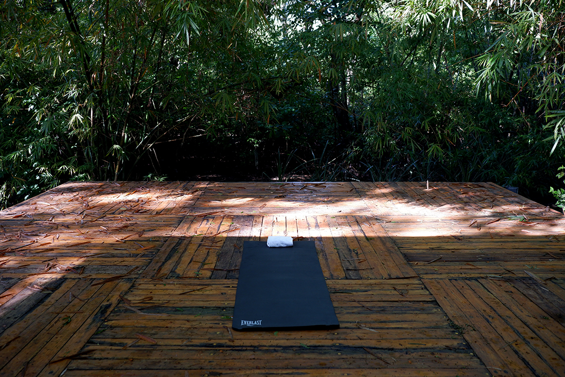 Sleep among the mangrove trees at El Mangroove Hotel: wood yoga platform in the garden, one yoga met on it; Costa Rica