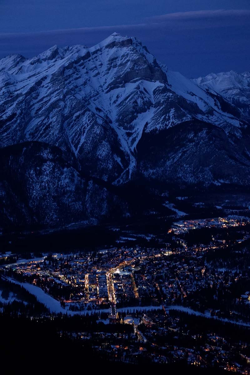 Five things to do in Banff for non-skiers: Sulphur Mountain at night, lightly lit village at the foot of it