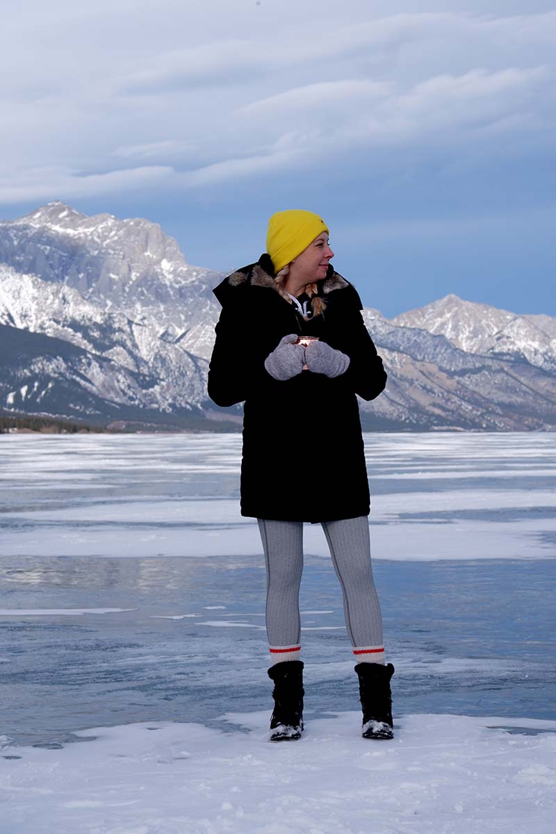 Five things to do in Banff for non-skiers: Abraham Lake, Kateryna standing on the snow patch with a hot cup of tea