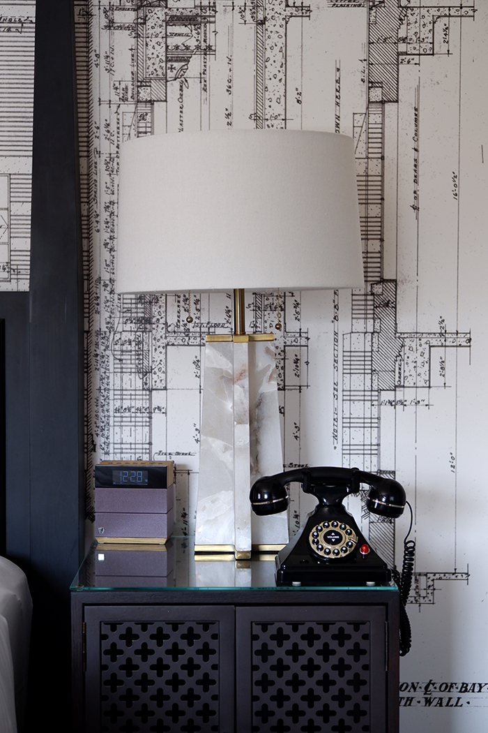 Everything you need to know about The Lodge at St. Edward State Park: image of a lamp and black rotary phone, behind is a decorative wallpaper with the blueprint of the original building 